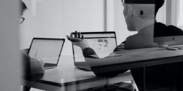 Two people sitting in front of laptops discussing why digital marketers should focus on user experience.