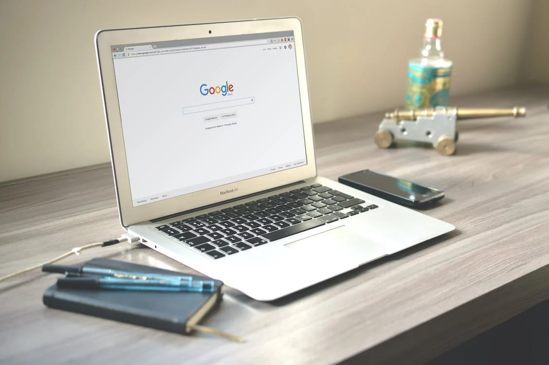 A silver laptop on an office desk displaying Google’s search engine page.